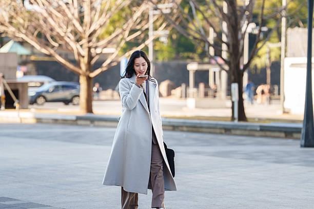 Woman in coat on phone outdoors
